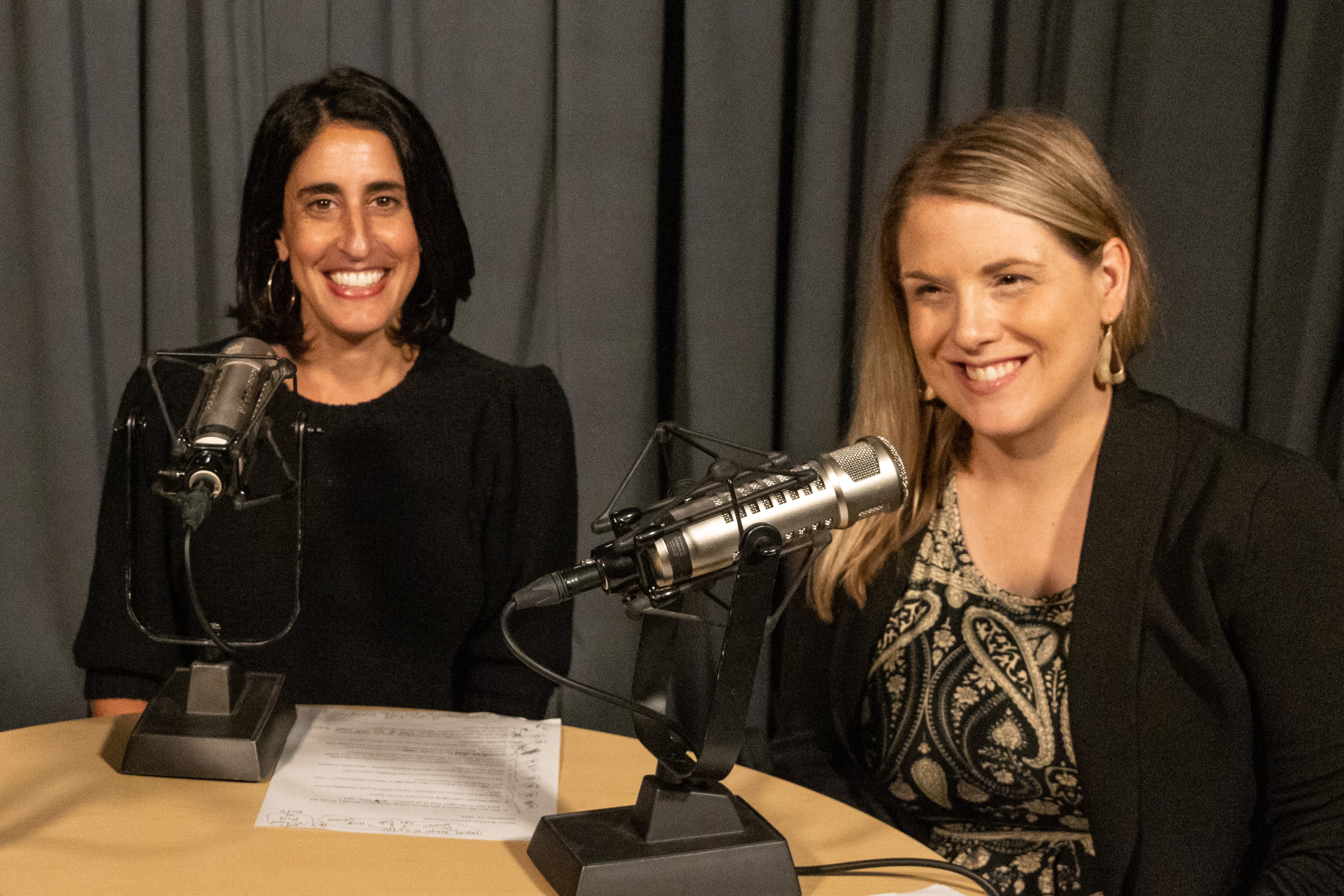 Hosts of the MOPD All Access Podcast sit at a wooden table behind microphones. 